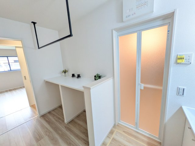 つくば市栗原　1期　新築戸建てのランドリースペース|バスルーム隣接で脱衣から洗濯までの流れがスムーズ。アイアンバーやカウンターを備え、家事スペースとしてはもちろん、収納やちょっとした作業台としても便利に活用できる機能的な空間です。