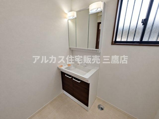 東久留米市前沢3丁目 西武新宿線 花小金井駅 中古戸建の独立洗面台|落ち着いたダークブラウンの収納扉と三面鏡を備えた独立洗面台です。横には窓があり、換気もしやすく明るい空間で朝の身支度ができます。