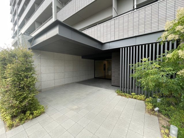 サーパスシティ土居田グランゲートのエントランス|石貼りの壁と植栽の緑が調和したエントランスは、ホテルのような上質さと親しみやすさを兼ね備えます。