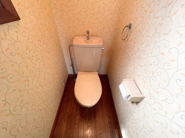 高江南1丁目　戸建てのトイレ|温かみのある木目調の床が特徴のトイレです。シンプルな設備で使いやすい空間となっています。壁紙の模様がアクセントになっており清潔感のある印象です。