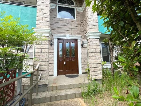 高江南1丁目　戸建ての玄関|重厚感のある石造りの外観が特徴的な玄関です。木製ドアがエントランスを引き立てています。両側の窓が採光を助け明るい印象となっています。階段のアプローチも広めに設計されています。