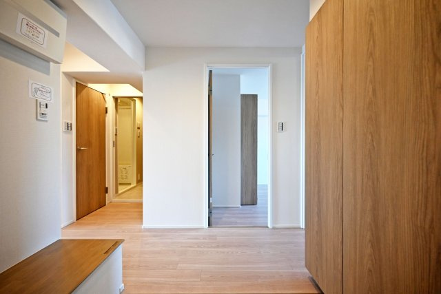 西宮セントポリア1号棟の玄関|玄関を入ると、木目の建具と明るいフローリングが目に入るすっきりとした空間。右手には高さのあるシューズボックスを備え、靴をまとめて収納できます。
