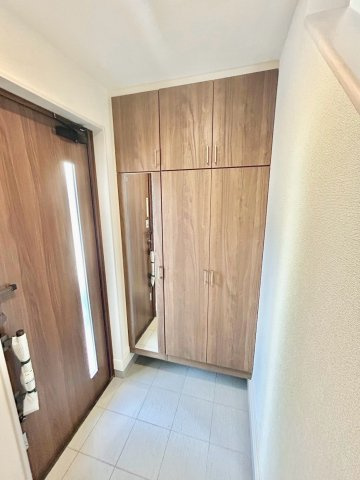 【仲介手数料無料】川越市岸町２丁目の玄関|姿見付きシューズクロークで、外出前の身だしなみチェックがスムーズに。靴やアウトドア用品をまとめて収納でき、玄関まわりがすっきり整う使い勝手の良い空間です。