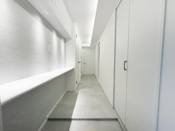 東明野ハイツの玄関|白を基調とした、明るく清潔感のある玄関。ダウンライトが壁面をやさしく照らし、帰宅するたびに心地よさを感じられる空間に仕上がりました。
