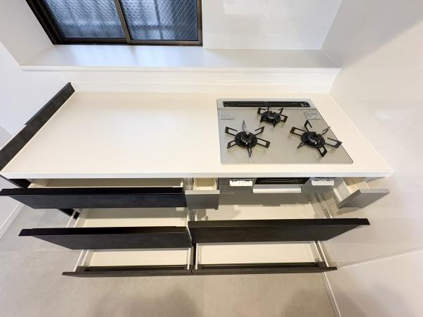 東明野ハイツのキッチン|コンロ下には、調理器具や鍋などをたっぷり収納できる引き出し収納を完備！必要なものをサッと取り出せる使い勝手の良さが魅力です。調理スペースも広く、毎日の料理がスムーズに進みます。
