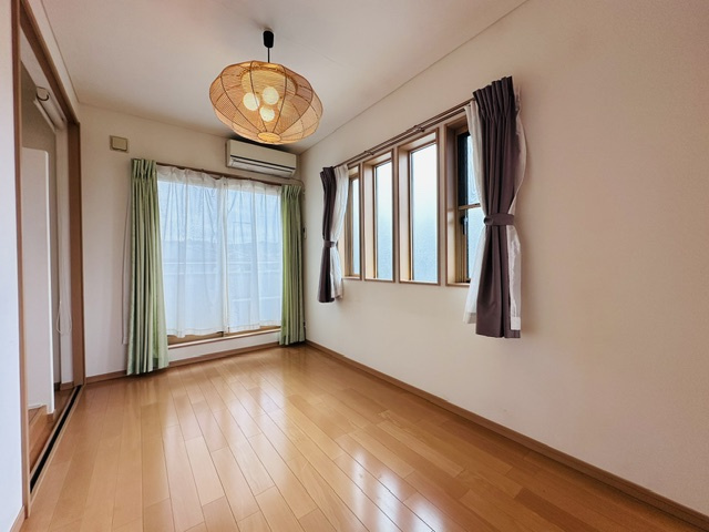 木津川市梅美台2丁目　　中古戸建の洋室|バルコニーに通じる大きな窓と4連の縦長窓から自然光が入る明るい室内。