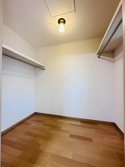 木津川市梅美台2丁目　　中古戸建の収納|両側にハンガーパイプと上部棚を備えたウォークインクローゼット。