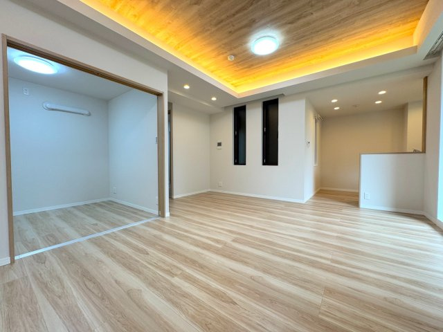 レクセルプラッツァせんげん台弐番館の居間・リビング|家族の笑顔が広がるリビングダイニングの別アングルです。天井アクセントクロスと間接照明が織りなす優しい陰影が、お部屋全体を上品でリラックスできる空間に引き立てます。思い思いの寛ぎの時間をお楽しみください