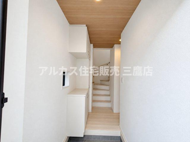【内覧動画公開中！】三鷹市上連雀7丁目 中央線 三鷹駅 新築戸建の玄関|木目調の天井と白い壁面が包み込む、明るく清潔感あふれる玄関スペースです。大容量のシューズボックスを備え、奥の階段へとスムーズにつながる使い勝手の良い動線です。