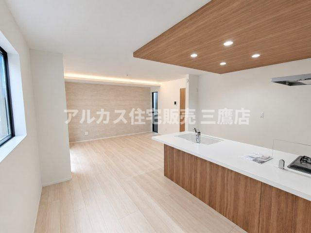 【内覧動画公開中！】三鷹市上連雀7丁目 中央線 三鷹駅 新築戸建の居間・リビング|対面キッチンからリビング全体が見渡せる開放的なレイアウト。木目の下がり天井とダウンライトがおしゃれな印象を与えます。
