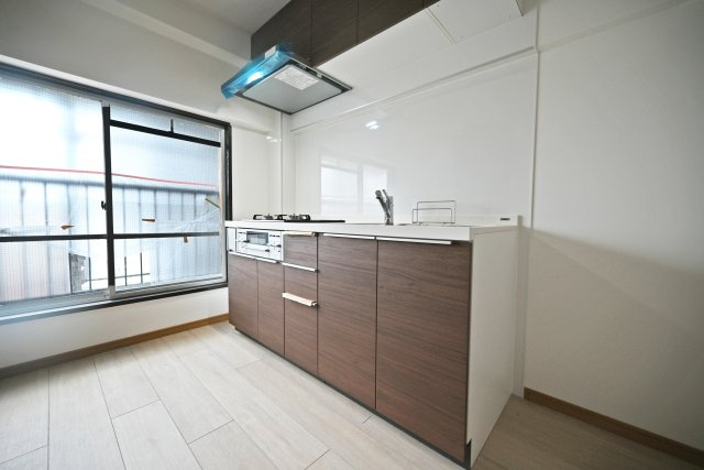 塚本東コーポA棟のキッチン|ダイニングキッチンから廊下を挟んだ位置にあるリビングスペース。アクセントクロスで彩られた空間にソファーセットやテレビボードを配置できます。