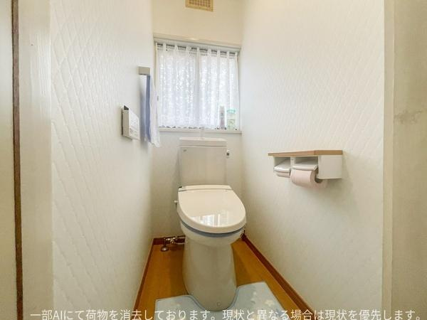 星和台一丁目　戸建てのトイレ|トイレは明るい光が差し込む窓付きの空間です。壁の質感や床材にもこだわりが感じられます。ペーパーホルダーやタオル掛けも設置されています。