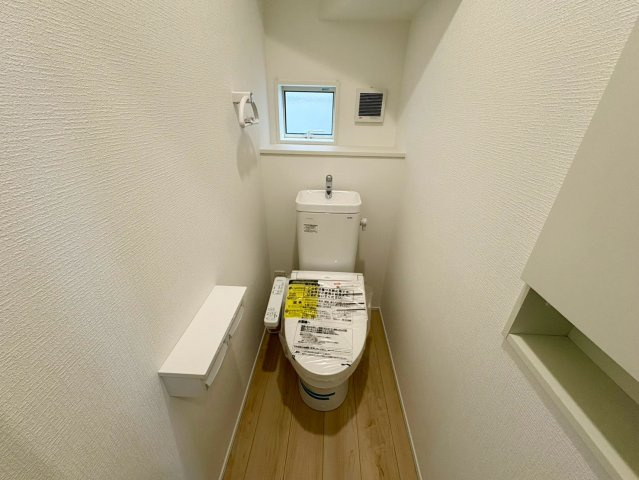 「値下げ！高知駅北の好立地」高知市比島町第1　新築一戸建てのトイレ|小窓からの自然光で明るく清潔なトイレ！トイレットペーパー等をスッキリ整頓できる棚付き。