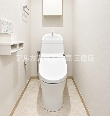 コートハウス三鷹のトイレ|清潔感のある白を基調とした温水洗浄便座付きトイレ。上部にはトイレットペーパーなどを整理できる吊戸棚収納を設置しています。