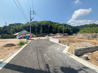 【前面道路含む現地写真】 | 廿日市市地御前北3丁目（全12区画）No５ | 敷地奥側から前面道路を見渡した様子。分譲地内はすっきりと舗装されており、車の出入りもスムーズに行えます。周囲には豊かな緑が広がり、開放感あふれる住環境です。