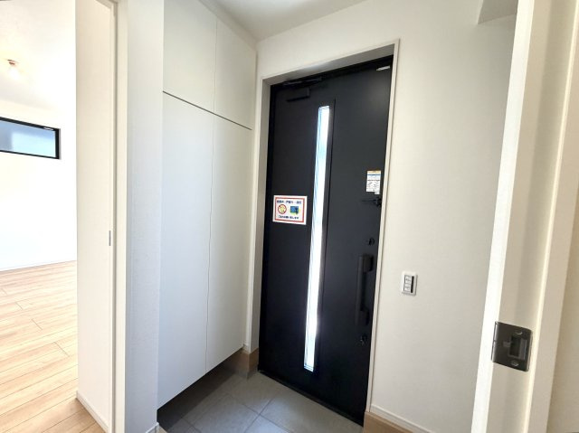 越谷市大沢１５期１号棟ケイアイグレース　新築戸建の玄関|明るい照明と清潔感のあるタイル床が印象的。来客時にも心地よい第一印象を与えてくれます。