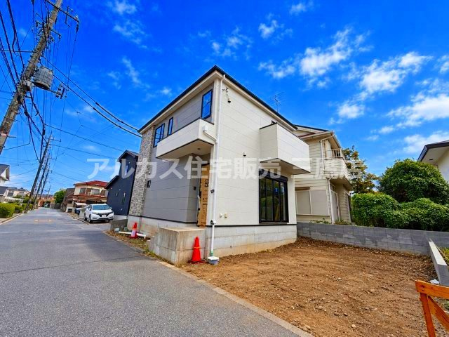 小金井市貫井南町1丁目 中央線 武蔵小金井駅 新築戸建の外観|南東または南西側から撮影した2階建て新築住宅の外観です。清潔感のある白い外壁にグレーのアクセントが施されており、手前の敷地部分は更地になっています。玄関ドアにはまだ保護用の養生シートが残っており、完成