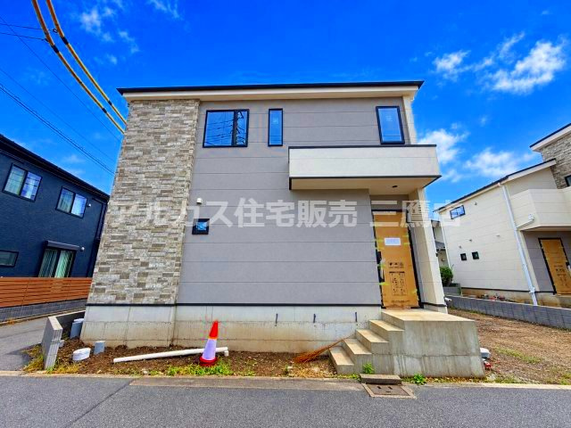 小金井市貫井南町1丁目 中央線 武蔵小金井駅 新築戸建の外観|建物の正面（玄関側）を垂直に捉えた1枚です。シックなグレーのサイディングと高級感のある石目調パネルの切り替えが印象的で、コンクリートの玄関ステップが配置されています。