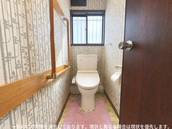 ふじが丘山手二丁目　戸建てのトイレ|窓付きで自然光が入るトイレです。壁面には手すりを設置し移動や立ち上がりをサポートします。落ち着いた色合いの内装です。スペースにゆとりがあり使いやすさも考慮されています。