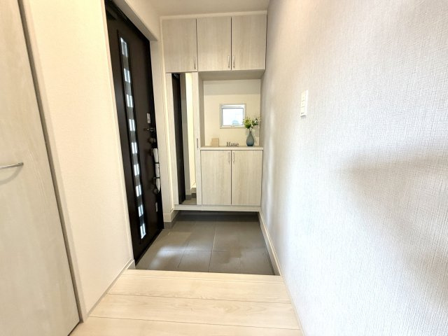 越谷市相模町６丁目１号棟　新築戸建の玄関|明るい照明と清潔感のあるタイル床が印象的。来客時にも心地よい第一印象を与えてくれます。