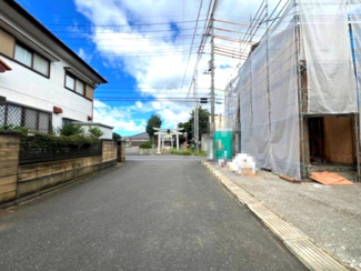 【前面道路含む現地写真】 | つくば市高見原第19　新築戸建 | 見通しの良い前面道路に面し、お車の出し入れもスムーズ。開放感のある立地で、毎日の暮らしにゆとりを感じられる住環境です。