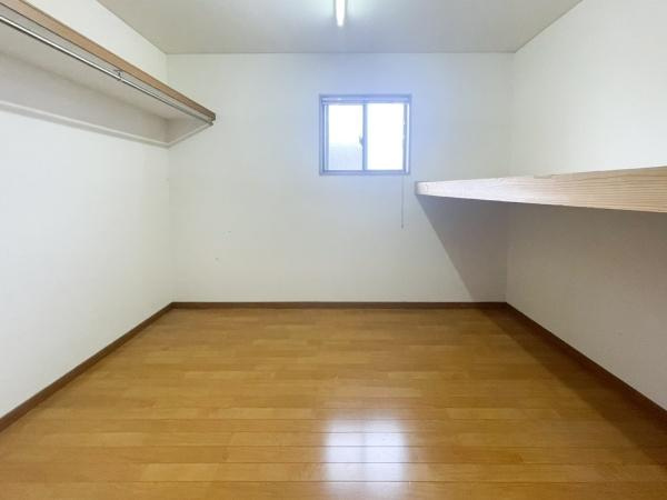 口戸　戸建ての収納|広々としたウォークインクローゼットです。窓が設置されているため明るい採光を確保できます。収納棚もしっかりと設けられており整理整頓がしやすい環境です。衣類や荷物の収納にも適しています。