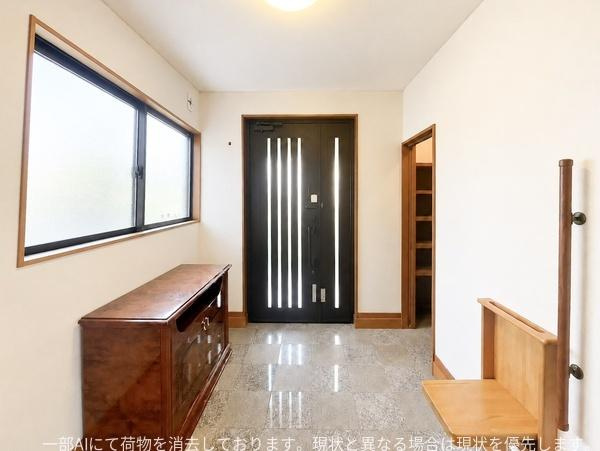 口戸　戸建ての玄関|広々とした玄関スペースが特徴です。明るい採光が印象的ですっきりとした印象です。収納も配置しやすいレイアウトになっています。段差や手すりがあり使いやすさが感じられます。