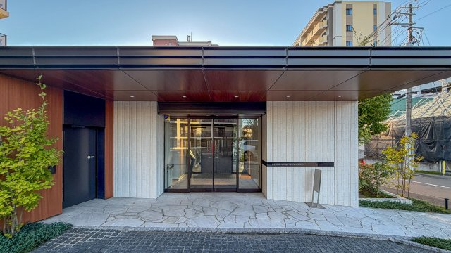 レジデンシャル泉中央|石張りのアプローチと木目調の大きな庇が迎えるエントランスです。