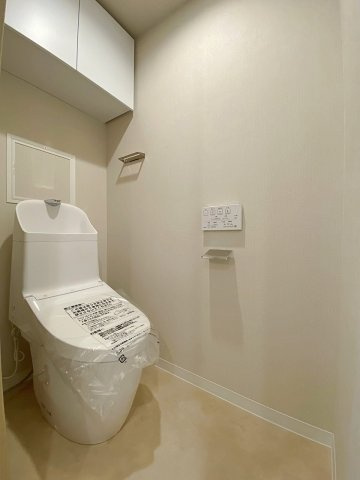 根岸ハイツ２号棟のトイレ|快適なウォシュレット機能を備えた新規交換済みの清潔なトイレ空間。毎日使う場所だからこそ、衛生面と居心地の良さにこだわりました。上部に収納スペースもあり、用品もすっきり収まります。