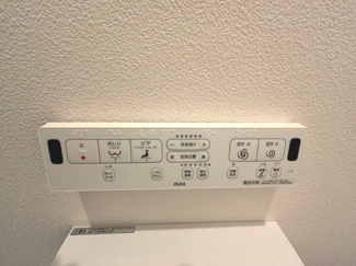 【トイレ】 | 廿日市市宮内【全4区画】No4 | 壁掛け式のトイレリモコン。スマートなスクエア型のデザインで、壁面のアクセントクロスとも調和しています。洗浄ボタンや各種機能がすっきりと配置されており、どなたでも直感的に操作が可能です。