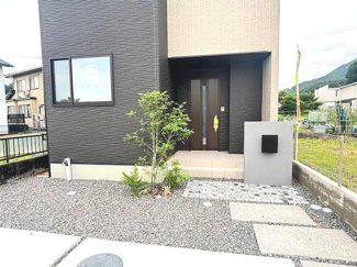 【玄関】 | 廿日市市宮内【全4区画】No4 | 植栽の緑が映える、シックな色調の玄関アプローチ。独立した機能門柱（ポスト）が設置されており、プライバシーを保ちやすい設計です。段差の少ない階段を数段上がって室内へ入ります。