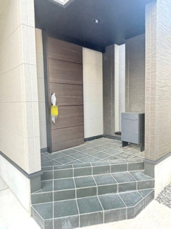 【玄関】 | 中区江波西1丁目（舟入南電停）全1区画【外構込み】 | 落ち着いた木目調の玄関ドアが、住まいの顔として上質な印象を与えます。庇（ひさし）があるため、雨の日でも濡れずに鍵を開け閉めできるのが魅力。モニター付きインターホン完備で防犯面にも配慮しています。