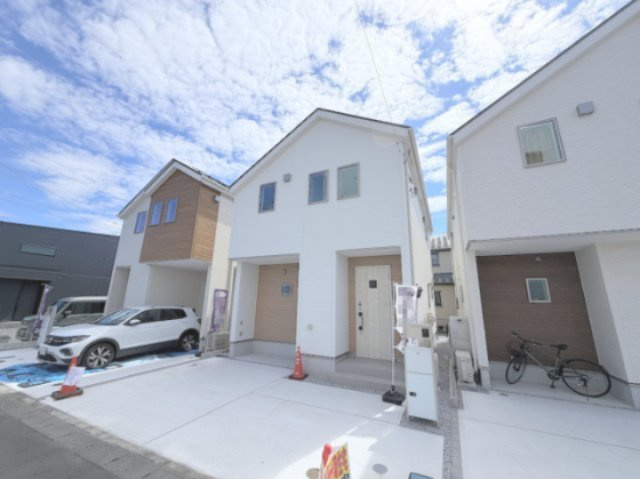 青梅市今寺4丁目の外観|ホワイトとベージュのツートンカラーがお洒落な新築分譲住宅の外観写真です。 明るい日差しの中で、洗練されたデザインが目を引きます。駐車場スペースもあり、快適な生活が想像できる物件です。