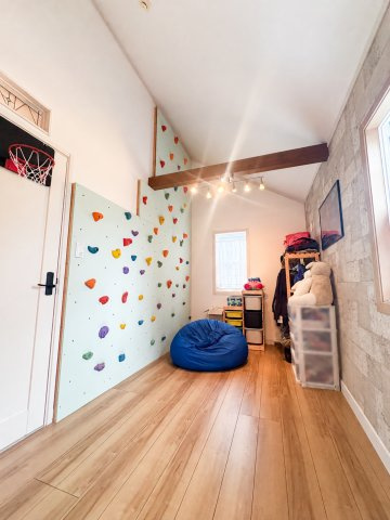 川越市大字下赤坂の中古一戸建の洋室|カラフルなボルダリングウォールのある10.6帖の子ども部屋です。
※掲載写真は生成AIを使用し、家具等を消す加工をしています。