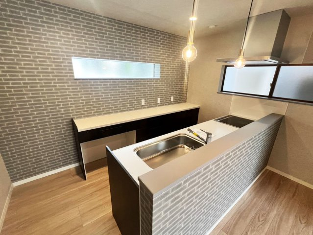 吉藤2丁目　リノベーション住宅のキッチン|リビングを見渡せる対面式キッチンに、大きめののカップボード（家電置き場・作業台）。調理家電を並べたり、配膳スペースとして活用したりするのに十分な広さがあります。