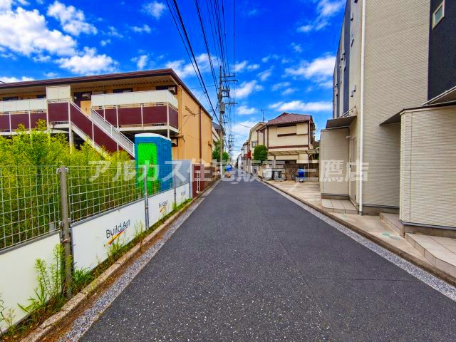 武蔵野市御殿山2丁目 中央線 三鷹駅 売地の前面道路含む現地写真|別角度から見た前面道路のカットです。道路沿いにはフェンスや仮設トイレ、建築関連の看板が設置されており、周囲の街並みと調和した閑静な環境となっています。