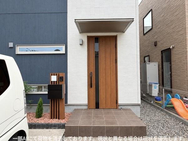 須賀二丁目　戸建ての玄関|スタイリッシュな木目調の玄関ドアが印象的です。すっきりとしたアプローチとシンプルな配色が住まいの雰囲気を引き立てます。エントランス前のタイルも広々としており使い勝手の良い空間です。