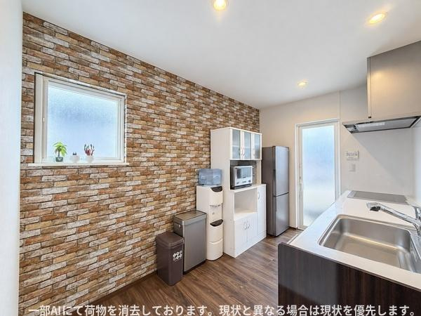 須賀二丁目　戸建てのキッチン|レンガ調のアクセントウォールが印象的なキッチンです。明るい窓から自然光が差し込みます。