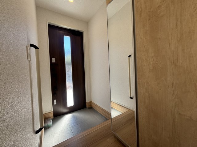 西区山田新町1丁目の玄関|木目調の玄関収納を備えた玄関です。靴や外出用品をまとめて収納でき、玄関まわりをすっきり保ちながら気持ちよく家族を迎えられます。