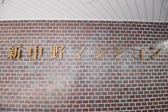 【現況写真】 | 新中野マンション | エントランスに掲げられた、マンション名を示す館銘板。さほど激しく主張はしませんが、しっかりと掲示されています。～即日のご見学可能～　お問合せはお気軽にどうぞ。
