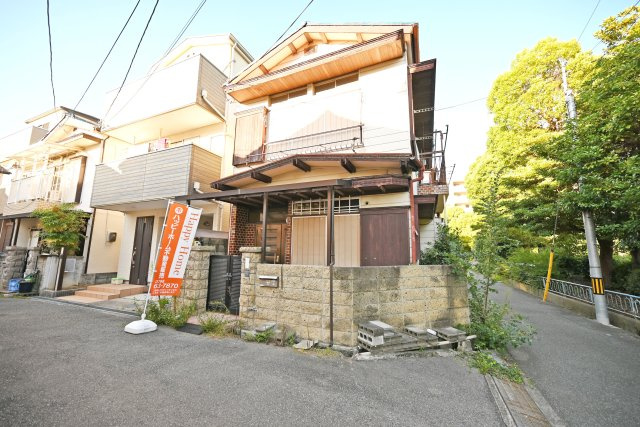 尼崎市東園田町7丁目建築条件付き売土地の前面道路含む現地写真|南東角地ならではの開放感が伝わる現地写真。二方向が道路に面し、隣接する公園の豊かな緑も印象的です。建築条件付き売土地につき、間取りや収納など、ご家族の暮らしに合わせた建物プランをご提案いたします。