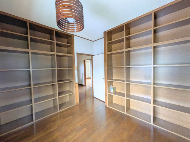 祝谷5丁目戸建ての洋室|壁一面に大きな作り付け棚を備えた洋室です。書籍やコレクションをきれいにディスプレイできます。