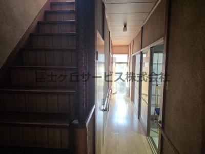 【設備】 | 森町三倉　中古住宅 | 既存部分の階段と、奥へ続くフローリングの廊下です。家の中に階段が2か所あるため、2階への行き来がしやすい間取り。廊下の両側には手すりが付き、突き当たりの出入口から外へも出られる便利な動線です。