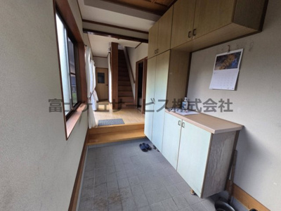 【玄関】 | 森町三倉　中古住宅 | ゆとりある広さの玄関です。天井近くまでの大容量シューズボックスを備え、靴や季節の道具もすっきり収納できます。窓からの自然光で明るく、正面には2階への階段とフローリングの廊下が続く使いやすい動線です。