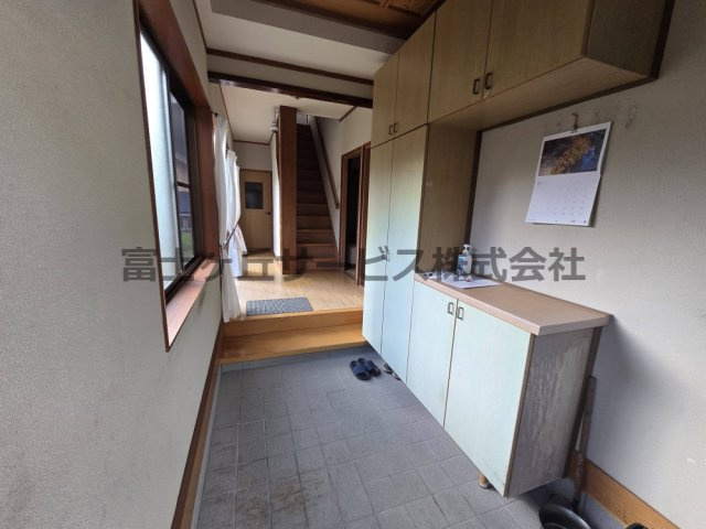 【玄関】 | 森町三倉　中古住宅 | ゆとりある広さの玄関です。天井近くまでの大容量シューズボックスを備え、靴や季節の道具もすっきり収納できます。窓からの自然光で明るく、正面には2階への階段とフローリングの廊下が続く使いやすい動線です。