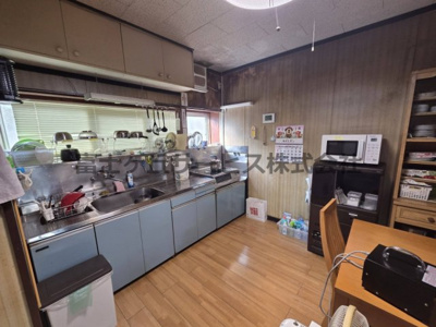 【キッチン】 | 森町三倉　中古住宅 | ステンレス天板の壁付けキッチンです。調理スペースにゆとりのある横長の作業台と、上部の吊戸棚で収納も確保。シンク前の窓から光と風が入り、明るく作業できます。お好みに合わせたリフォームのベースにも。
