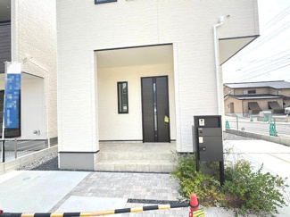 【玄関】 | 安佐南区伴中央2丁目（伴中央駅）No1 | ゆとりある広さの玄関ポーチが、日々の出入りを快適にサポートします。機能門柱を設置し、すっきりとした印象に仕上げています。足元はタイルと舗装で綺麗に整備され、清潔感のあるエントランスです。