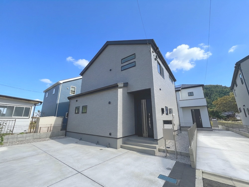 日の出町大久野の外観|グレーとブラックのツートンカラーがお洒落な新築分譲住宅の外観写真です。 明るい日差しの中で、洗練されたデザインが目を引きます。駐車場スペースもあり、快適な生活が想像できる物件です。