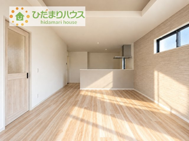 【居間・リビング】 | つくばみらい市陽光台2期　新築戸建 | 対面キッチンから家族の顔が見えるリビング。木目のアクセント壁に日差しが差し込む明るい空間です♪
※AIで作成したイメージです。床材・壁紙・色味は実際と異なる場合があります。