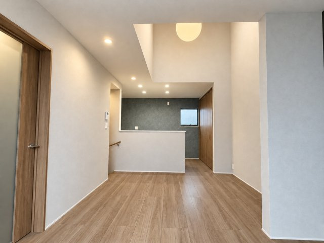 戸建 城陽市富野鷺坂山の居間・リビング|吹抜けが生み出す開放感たっぷりのLDK♪ 高い天井と温かみのある木目調のフローリングが心地よい空間を演出！グレーのアクセントクロスが映える、おしゃれな住まいです♪